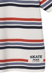 Short-sleeve striped t-shirt in cream, featuring horizontal stripes in navy, red, and light blue. Includes a white patch labeled "SKATE PARK."