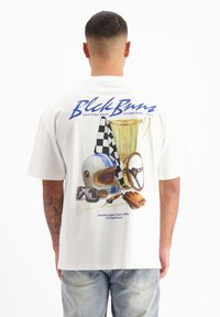 Witte t-shirt met een kleurrafische afbeelding van race-items, waaronder een trofee, helm, geblokte vlag, stuurwiel en handschoenen.