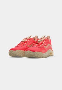 Pair of bright red hiking shoes with beige soles and laces, featuring brand logo and rugged tread for outdoor use.