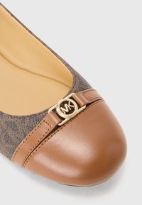 Ballet flat with a brown textured upper, smooth brown cap toe, and a gold logo accent. Features a rounded shape and cushioned interior.