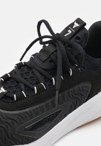 Sneaker sportivo nero con parte superiore in maglia testurizzata, suola bianca spessa, lacci annodati e logo di un toro sulla linguetta e sul passante anteriore per i lacci.
