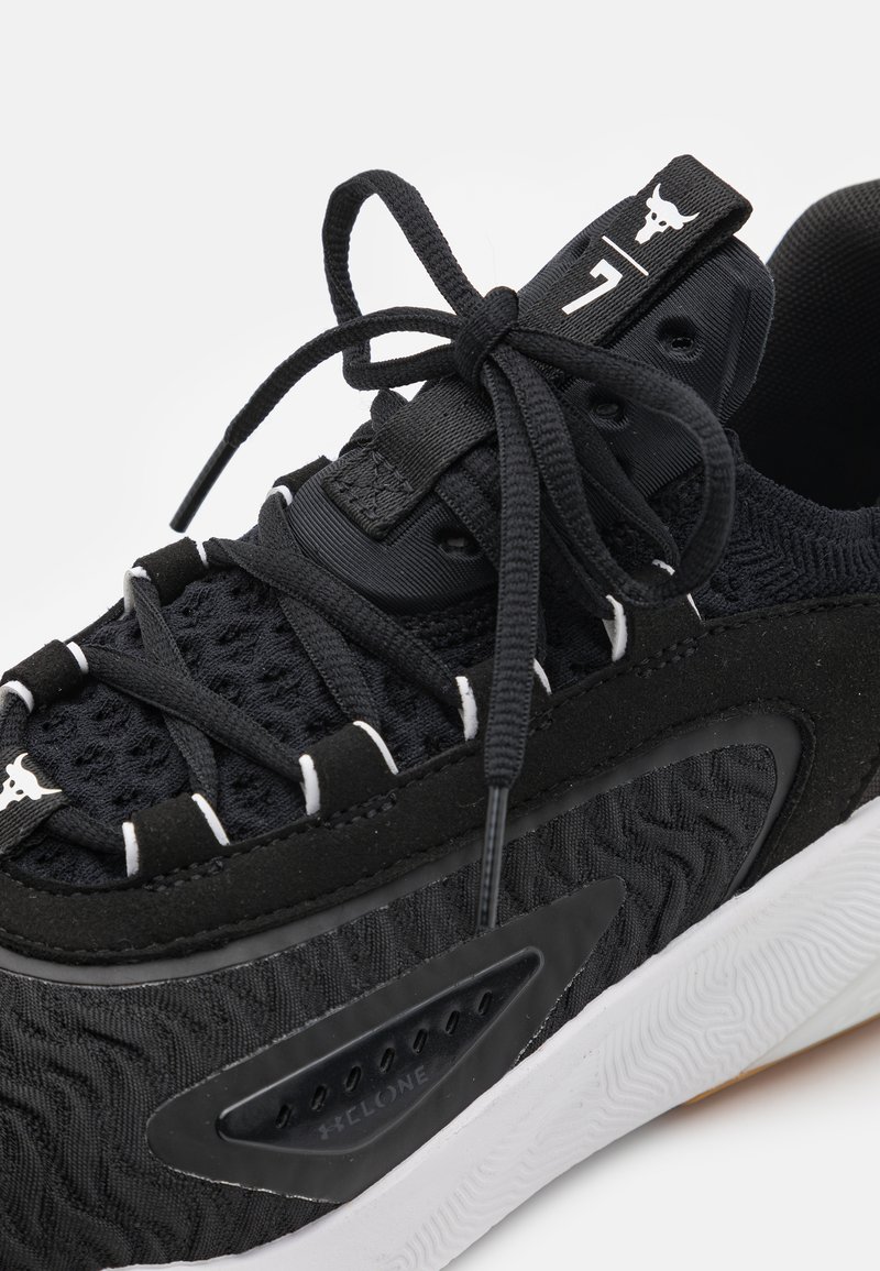 Zapatilla deportiva negra con upper de punto texturizado, suela blanca gruesa, cordones atados y un logo de toro en la lengüeta y el lazo frontal de los cordones.