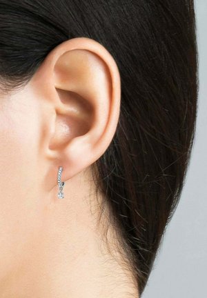 Pendiente de aro de plata con un diseño curvado, adornado con pequeños cristales transparentes, colgando con un acento en forma de cuadrado en la parte inferior.