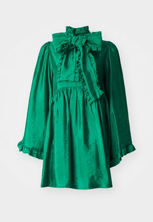 Abito verde in satin con collo alto e grande fiocco, caratterizzato da dettagli arricciati al colletto e alle maniche, e una silhouette svasata.