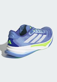 Blue running shoe with a textured upper, white three stripes, and green accents. Features a cushioned sole and a rounded heel design.