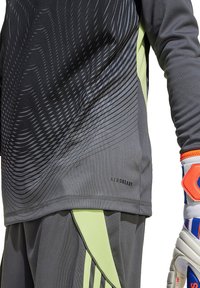 T-shirt de sport à manches longues grise avec un motif texturé, des accents verts et un logo "AEROREADY" près de l'ourlet.