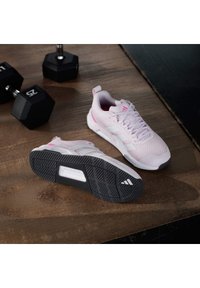 Αθλητικά παπούτσια σε ανοιχτό ροζ χρώμα με υφαντό μενούμενο επάνω μέρος και λευκές λεπτομέρειες, με μαύρη ελαστική σόλα που έχει σχέδια πρόσφυσης και λογότυπο.