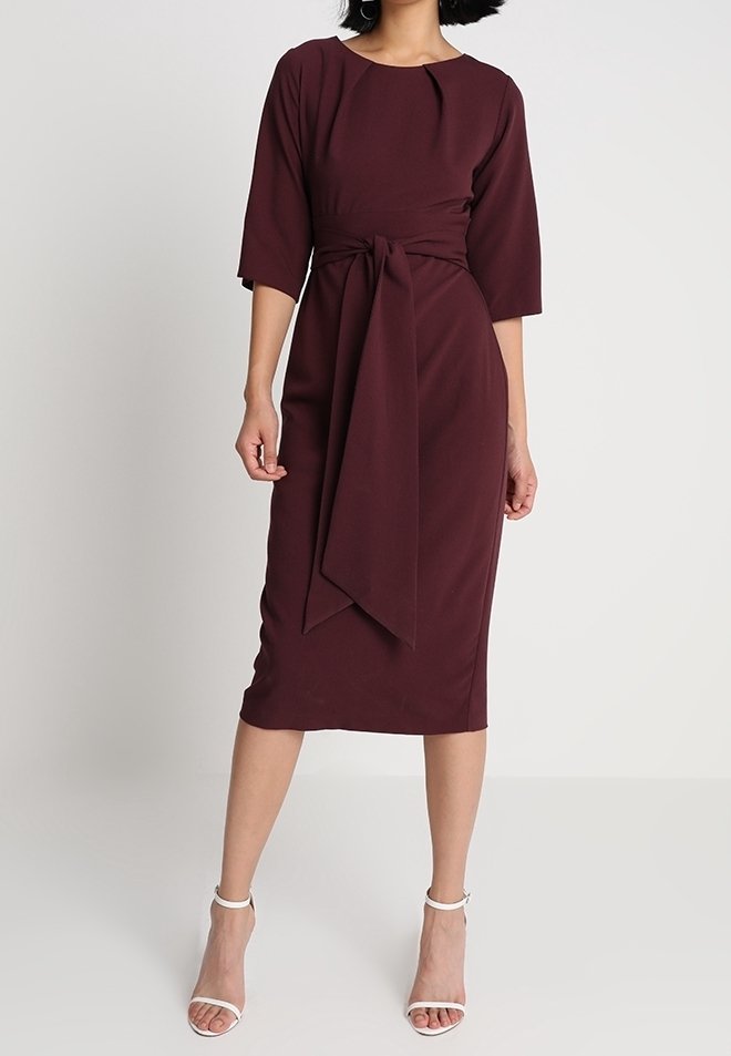 Robe portefeuille bordeaux avec une taille cintrée, des manches trois-quarts et un ourlet à hauteur des genoux. Texture lisse avec un détail de ceinture nouée à la taille.