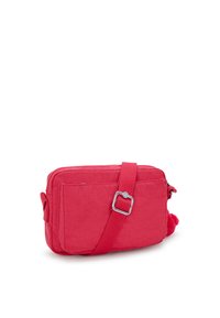 Röd crossbody-väska tillverkad av slitstarkt tyg, med dragkedjestängning, justerbar rem och pom-pom-detalj på sidan.