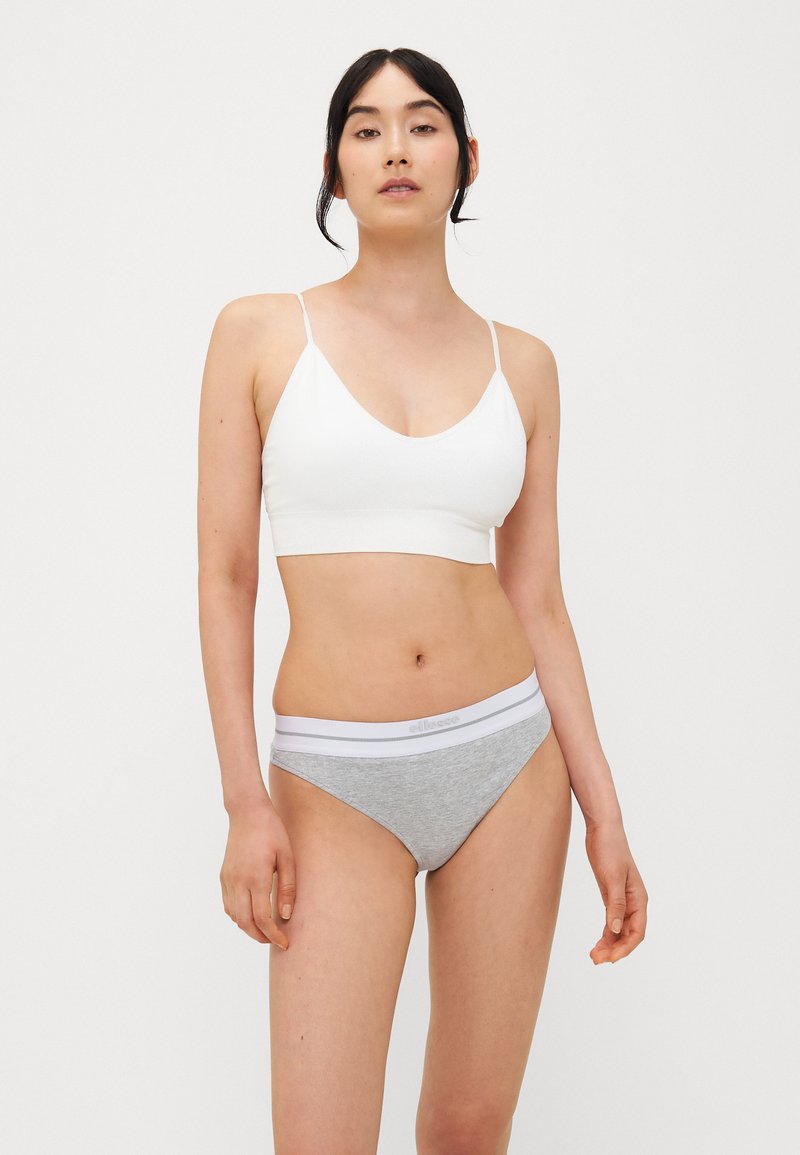 Soutien-gorge blanc avec des bretelles fines et un décolleté en V profond, associé �à une culotte grise avec une ceinture élastique blanche. Texture de tissu douce.