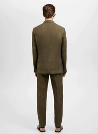 Costum croiț din material texturat, de culoare maron, având sacou cu deschidere simplă și pantaloni asortați. Design simplu și croi normal.