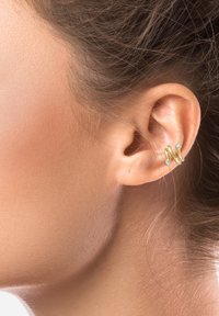 Gold- und silberne gedrehte Ohrschmuck mit zwei kleinen klaren Edelsteinen, die am Ohr eines Models getragen werden und ein modernes, minimalistisches Design zeigen.
