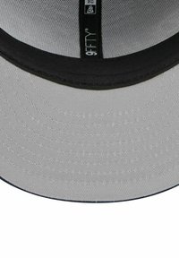 Casquette en tissu gris avec une visière noire, dotée d'une doublure intérieure texturée, de détails de couture et d'une étiquette 9FIFTY au centre.