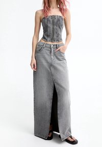 Zwart denim twee-delig outfit met een korte strapless top met verticale naden en een lange rok met een voorkantinscheuring en zijzakken.