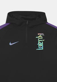 Czarna bluza Nike z pół-zipem, fioletowymi akcentami na ramionach oraz iryzującym tekstem "Kylian" i logo swoosh na klatce piersiowej.