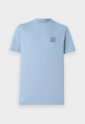 T-shirt en coton bleu clair avec un col rond et des manches courtes. Présente un petit logo carré sur la poitrine gauche. Texture douce, coupe décontractée.