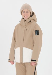 Giacca isolata beige con sezione inferiore bianca, cappuccio regolabile, tasca sul petto con zip e dettagli neri sui polsini. Texture morbida e liscia.