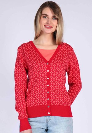 Red cardigan with heart pattern, V-neck, long sleeves, and button front. Ribbed cuffs and bottom hem. Layered with a light top.