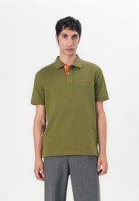 Oliven grønn polo-skjorte med klassisk krage; oransje innside på knappestolen; brodert logo på brystet; kortermet; glatt bomullsstoff.