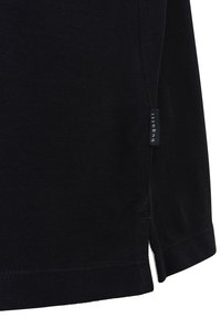 Schwarzes Baumwoll-T-Shirt mit strukturiertem Stoff, seitlichen Schlitzen am Saum und einem kleinen Markenlabel an der unteren linken Naht.