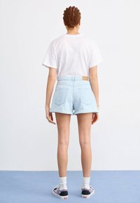 Svetlo modri denim šortsi imajo visok pas, zavit rob, dvojne zadnje žepe in usnjeno oznako na pasu. V kombinaciji z belo majico.