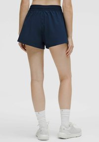 Marinblå idrottsshorts med elastisk midja, med en lös passform och en slät yta, i kombination med vita strumpor och ljusa sneakers.