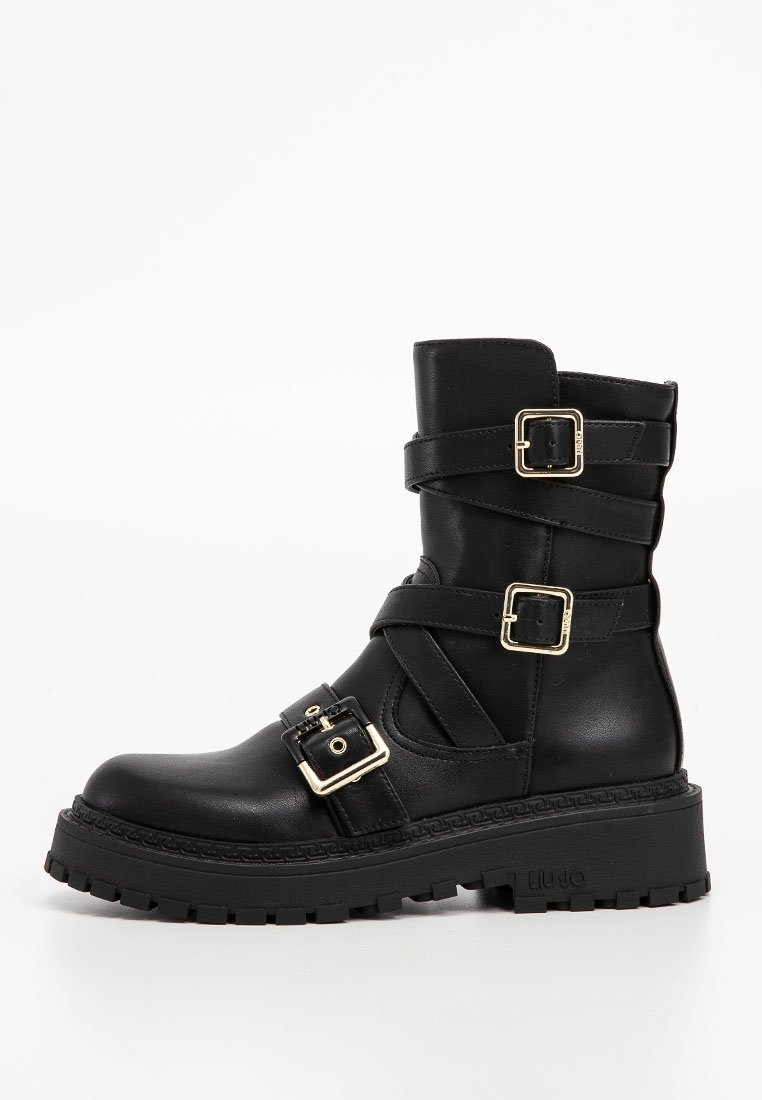 Schwarze Leder-Stiefelette mit zwei goldenen Schnallen, breiten Riemen und einer klobigen Gummisohle. Glatte Textur und abgerundete Zehenform.