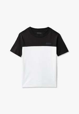 Maglietta a maniche corte in bianco e nero con sezione superiore nera, sezione inferiore bianca, scollo tondo e piccolo logo Calvin Klein sul petto.