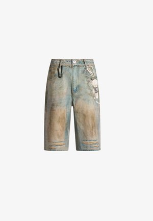 Shorts in denim con toppe logore, accessorio a catena sul lato destro e un moschettone nero agganciato al passante sinistro della cintura.