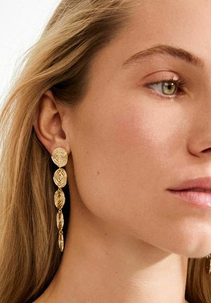 Auksinės, spiraliniu raštu puoštos auskarai su pailgintu dizainu, kuriuos sudaro sluoksniuotos apskritos formos, elegantiškai kabančios nuo ausies spenelio.