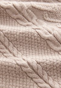 Țesătură tricotată bej cu modele texturate, având un design de tip cablu și o textură moale și confortabilă. Groasă și caldă, cu un finisaj striat.