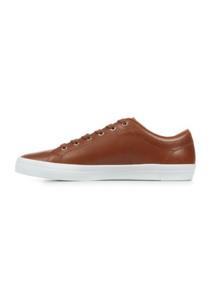 Zapatilla de cuero marrón con un acabado suave, suela de goma blanca y seis ojetes para los cordones. Diseño simple, punta redonda y perfil bajo.