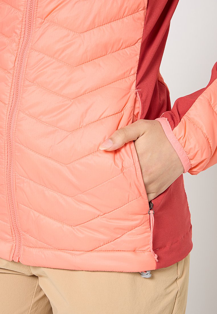 Chaqueta ligera acolchada con un diseño en tonos coral y rojo. Cuenta con un bolsillo con cremallera y puños elásticos para un ajuste seguro. Textura suave y lisa.