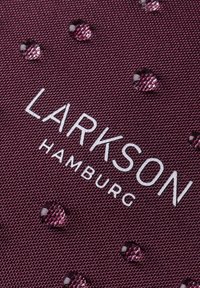 Burgundy textil med struktur som har en upphöjd logotyp "LARKSON HAMBURG" i vitt, prydd med glänsande lila vattendroppar.