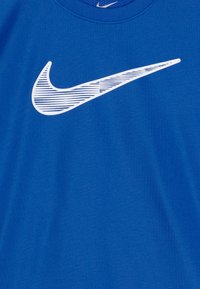 Blå bomulls T-shirt med en vit Nike Swoosh-logotyp och horisontella ränder. Rund halsringning och slät textur.