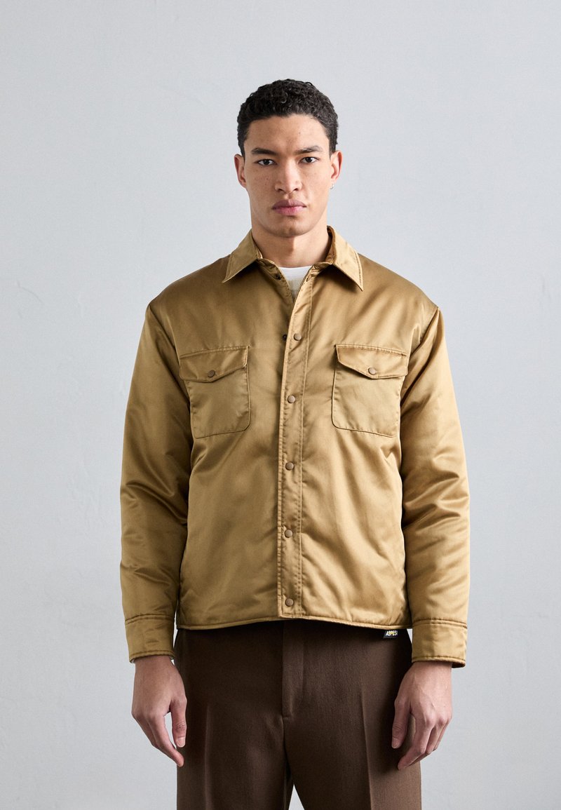 Khaki jacket with button closure, two chest pockets, and a smooth, glossy texture. Features a folded collar and a tailored fit.