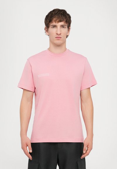 T-shirt en coton rose à manches courtes, avec un col rond et des détails en texte blanc sur le côté gauche. Texture douce et coupe régulière.