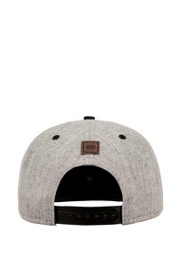 Grå snapback-cap med teksturert stoff, svart plastlukking og en brun logopatch bak. Har syddetailer.