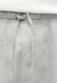 Pantalon en lin gris clair avec taille élastique et cordon à nouer au centre devant.