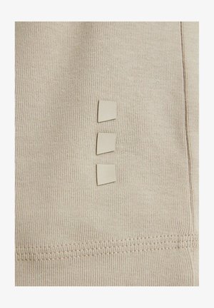 Beige stof met een ribbelstructuur, met drie kleine vierkante tabs die verticaal zijn uitgelijnd. Zichtbare stiksels langs de rand.