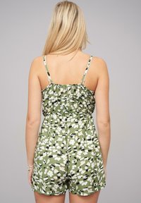 Roheline lilleline kombinesoon, millel on reguleeritavad õhukesed rihmad, elastne vöökoht ja vabalt istuv lõige. Omab valgeid ja musti lillemustreid.