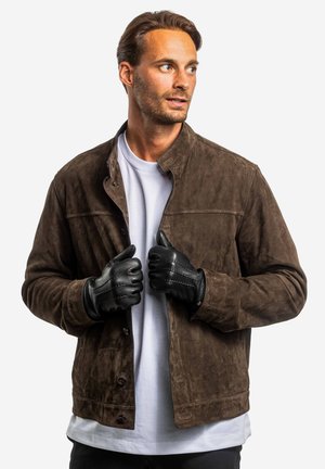 Brown suede jacket with a collar and front buttons, paired with black leather gloves, worn over a white t-shirt. Smooth texture finish.