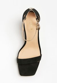 Sandale à talons hauts en daim noir avec un bout carré, dotée d'une sangle à boucle dorée et d'une semelle intérieure beige avec un logo.