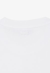 T-shirt blanc à col rond avec un petit logo crocodile blanc brodé, discret, centré près du col au dos.