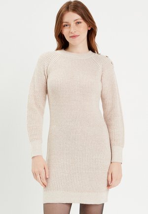 Vestido de punto en beige claro, con textura acanalada, mangas largas y detalles de botones en el hombro, con una silueta ajustada.