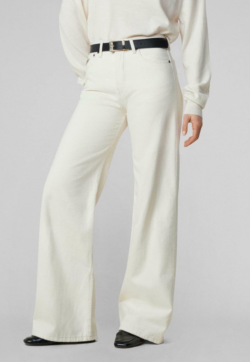 Jeans de pierna ancha en color crema, hechos de una mezcla de algodón, con cintura alta, bolsillos frontales y un cinturón negro con una hebilla dorada.