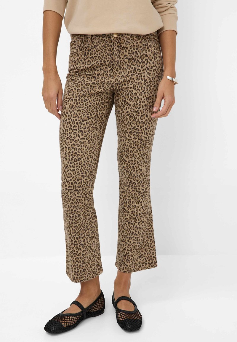 Luipaardprint broek in bruin en zwart, met een aansluitende taille en uitlopende pijpen, gecombineerd met zwarte mesh ballerina's. Soepele stoftextuur.
