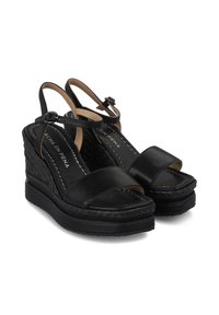 Sandalias de cuña de cuero negro con dos correas frontales anchas, correa en el tobillo y textura trenzada en el tacón de cuña. Presentan costuras en contraste.