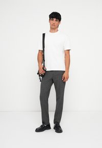 Witte korte mouwen t-shirt, grijs geblokt patroonbroek, zwarte schoenen en een zwarte schoudertas. Eenvoudig en modern ontwerp.