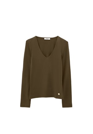 Camicia a maniche lunghe verde oliva con scollatura a V e piccolo marchio metallico vicino all'orlo, esposta su sfondo bianco.